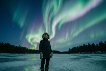 Femme en parka arctique observant les aurores boréales sur un lac gelé en Laponie finlandaise