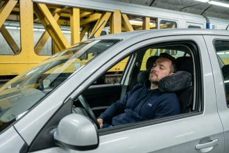 Homme endormi dans sa voiture à bord du train Eurotunnel sous la Manche avec oreiller de voyage