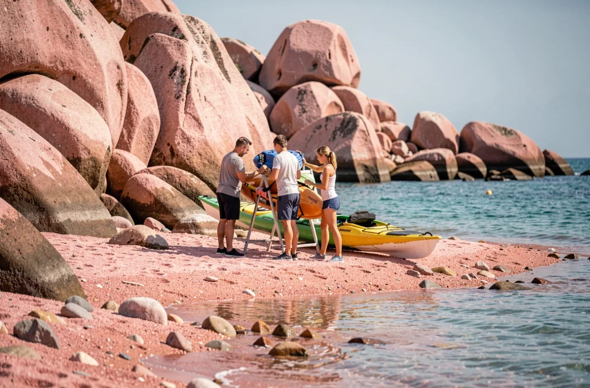 Famille équipée pour une excursion en kayak sur la plage de granit rose en Bretagne lors d'une activité touristique estivale