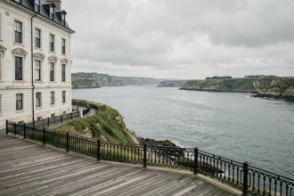 Vue panoramique sur la côte normande avec une façade d'hôtel historique dominant la Manche sous un ciel nuageux typique de la région